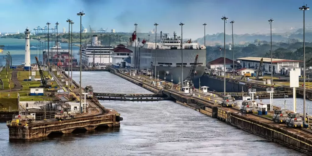 Schiffe passieren eine Schleuse des Panamakanals, umgeben von technischen Anlagen, Kränen und Gebäuden – ein zentrales Nadelöhr des internationalen Handels.